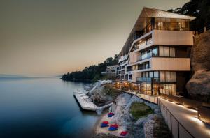 a building next to a body of water with umbrellas at Boutique & Design Hotel Navis - Small Luxury Hotels of the World in Opatija