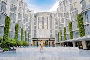 una mujer caminando frente a un edificio en The Salil Hotel Riverside Bangkok, en Bangkok