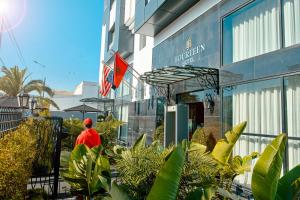 a man standing outside of a building with plants at Fourteen Hotel Ain Sebaa in Casablanca