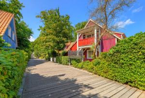 a red house on a wooden walkway next to houses at Dünenhaus Ückeritz UnserUsedomDe FeWo ca40qm mit Parkplatz direkt am Strand 6I2 in Ueckeritz