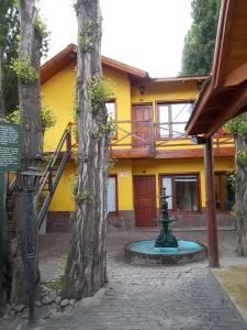 a yellow house with a fountain in front of it at Aparts de los Pajaros in El Calafate