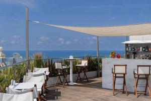 a patio with chairs and a bar with the ocean in the background at Grand Hotel Principe Di Piemonte in Viareggio