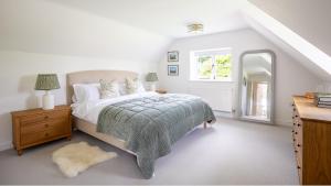 a white bedroom with a bed and a window at Patch Hill House in Finstock