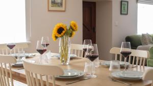 a table with a vase of sunflowers and wine glasses at Patch Hill House in Finstock +16 photos