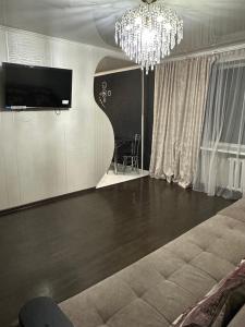 een woonkamer met een televisie en een kroonluchter bij 2 ком люкс в центре города in Karagandy