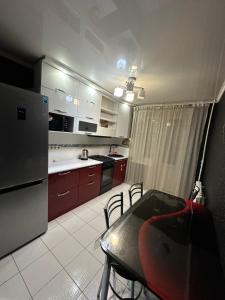 een keuken met een tafel en een koelkast bij 2 ком люкс в центре города in Karagandy