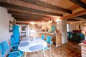 una cucina con un tavolo bianco e sedie blu di La Maison des Chênes - Piscine et grand terrain arboré dans une ambiance bucolique. a Cahuzac-sur-Vère