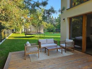a patio with a couch and chairs on a deck at Domek w Lesie z Kominkiem i Ogrodem Niedalino in Niedalino