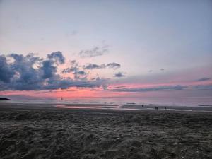 a group of people walking on the beach at sunset at La Maison des Saveurs in Trouville-sur-Mer