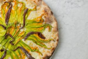 a pizza with green vegetables on top of a table at Grand Hotel Principe Di Piemonte in Viareggio