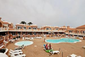 un complejo con piscina y gente sentada en sillas en Esmeralda Sunny Relax, en Caleta de Fuste