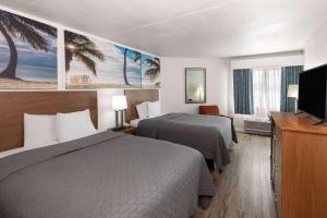 a hotel room with two beds and a flat screen tv at Days Inn by Wyndham Biloxi Beach in Biloxi