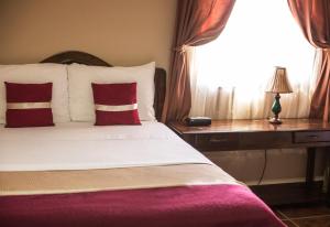 a bedroom with a bed with red pillows and a window at La Bellota Hotel in Siguatepeque