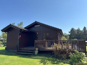a log cabin with a porch and a deck at The Vital Spark in Gatehouse of Fleet