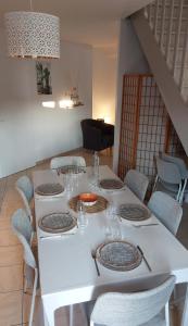a white table with chairs and a white table with glasses at Maison au coeur de Meschers - proche des plages in Meschers-sur-Gironde