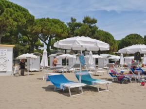 a beach with lounge chairs and umbrellas on the sand at Casa Zuliani - bilocale in Costa Azzurra in Grado