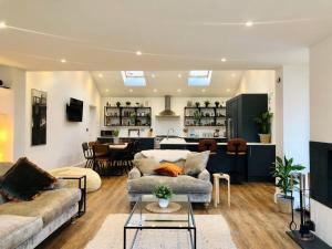 a living room with two couches and a kitchen at The Cuckoo's Retreat - Luxurious home with private garden & jacuzzi in Kenwyn