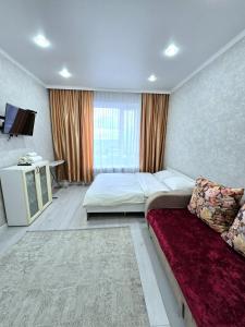 een slaapkamer met een groot bed en een bank bij Аэропорт 10 минут жк Будапешт163 in Astana
