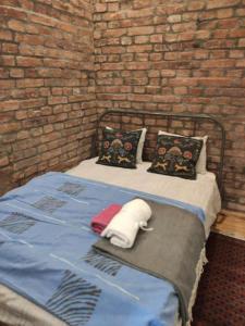 a bed with two pillows and a brick wall at Golden Age Hollywood PROMO PRICE! in Vračar (historical)