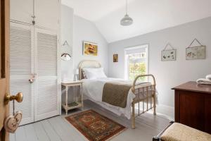 a white bedroom with a bed and a window at Charming country cottage in quiet rural setting in Pavenham
