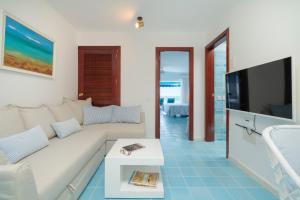 a living room with a white couch and a tv at Sea Front Caletón Suite in Los Pocillos