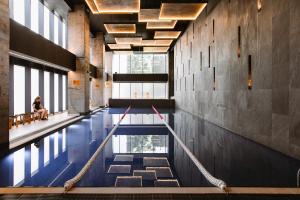 a swimming pool in a building with a woman sitting on a bench at Zen Studio 1 with balcony in Bucharest