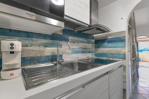 a kitchen with a stainless steel sink and blue tiles at Mono4Posti Vista Mare Il Portolano in Porto Azzurro