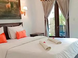 a bedroom with a white bed with orange pillows at Padanta Gili Trawangan in Gili Trawangan