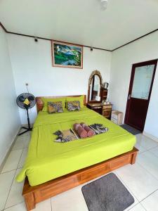 a bedroom with a large yellow bed with a green blanket at pinggan box glamping in Bangli