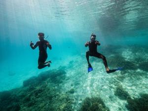 two people swimming in the water in the ocean at Homestay Tapor Aikos in Besir