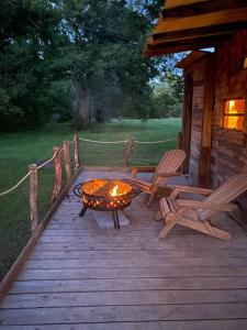 ハンツビルにあるPecan Grove Cabinの焚き火台と椅子2脚を備えた木製デッキ