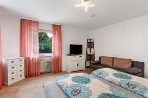 a bedroom with two beds and a couch and a television at Fewo unter der Kirche in Broggingen