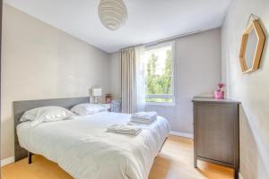 a white bedroom with a large bed and a window at Bel appartement Bordeaux centre in Bordeaux