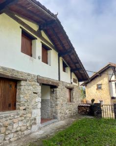 a stone house with wooden windows and a yard at Kanala, estupendas vistas al Urdaibai in Canala