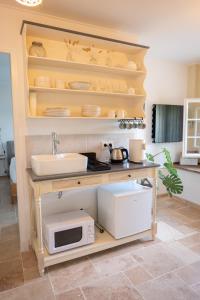 a kitchen with a counter with a sink and a microwave at Les Deux Petits Pois in Fanjeaux