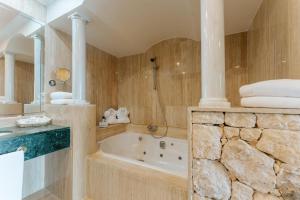 a bathroom with a tub and a stone wall at R2 Rio Calma in Costa Calma