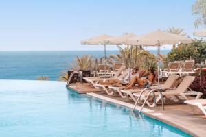 a group of people sitting on chairs next to a swimming pool at R2 Rio Calma in Costa Calma