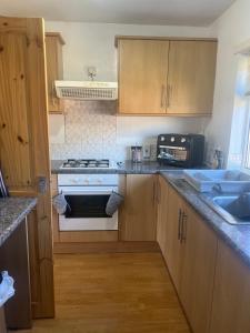 a kitchen with wooden cabinets and a white stove top oven at Cozy 2 BDRM Apartment Nr the World Heritage Site of Saltaire in Saltaire