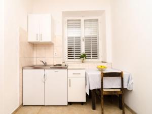 a kitchen with white cabinets and a table and chairs at Guest House Kiko - Apartment with Balcony A5 in Pomena