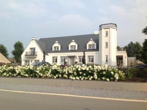 ein weißes Haus mit weißen Blumen davor in der Unterkunft Villa Reynaert in Opoeteren