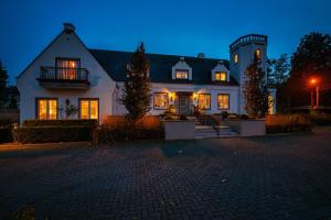 ein großes weißes Haus mit eingeschaltetem Licht in der Unterkunft Villa Reynaert in Opoeteren