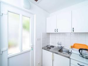 a kitchen with white cabinets and a sink and a window at Apartments Zarac - One Bedroom Apartment with Balcony and Sea View Milanka in Zaton