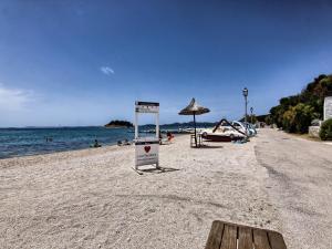 a beach with an umbrella and people on the water at Apartments Victoria - One Bedroom Apartment with Terrace A2 in Pakoštane