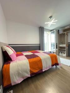 a bedroom with a bed with a colorful blanket at Disney en famille&Appart Calme et Spacieux in Magny-le-Hongre