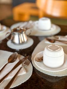 a wooden table with white plates and silver utensils at Arcadas Hotel in Caçapava +15 photos