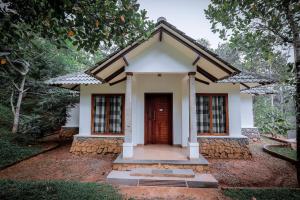 ein kleines weißes Haus mit einer roten Tür in der Unterkunft Century Village Resort in Mananthavady