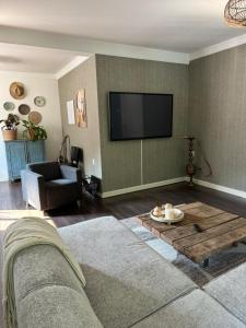 a living room with a couch and a tv on the wall at Appartement Nu in Eersel