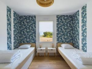 two beds in a room with a window at Maison pour 6 adultes avec piscine in Notre-Dame-de-Riez +25 photos