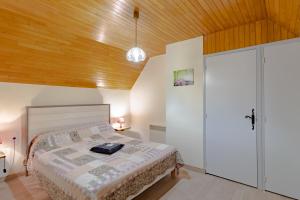 ein Schlafzimmer mit einem Bett und einer Holzdecke in der Unterkunft Le Petit Pech in Le Sirey