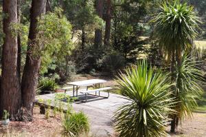 a picnic table in a garden with trees and plants at Oyster Cove Chalet in Kettering